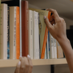 hand pulling a book off the shelf \ hero image for how to sell your book using a reader persona