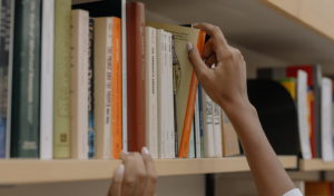 hand pulling a book off the shelf \ hero image for how to sell your book using a reader persona
